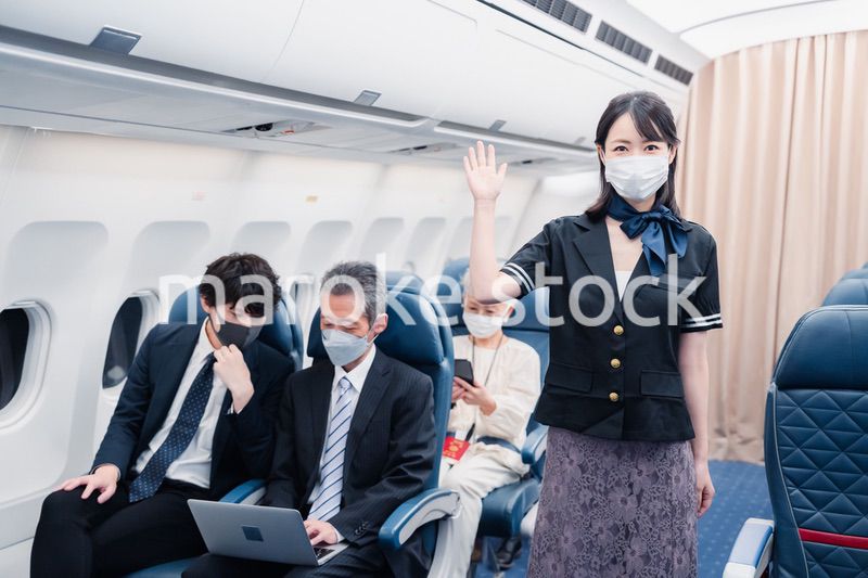 マスクをしてお客様の案内をするキャビンアテンダント