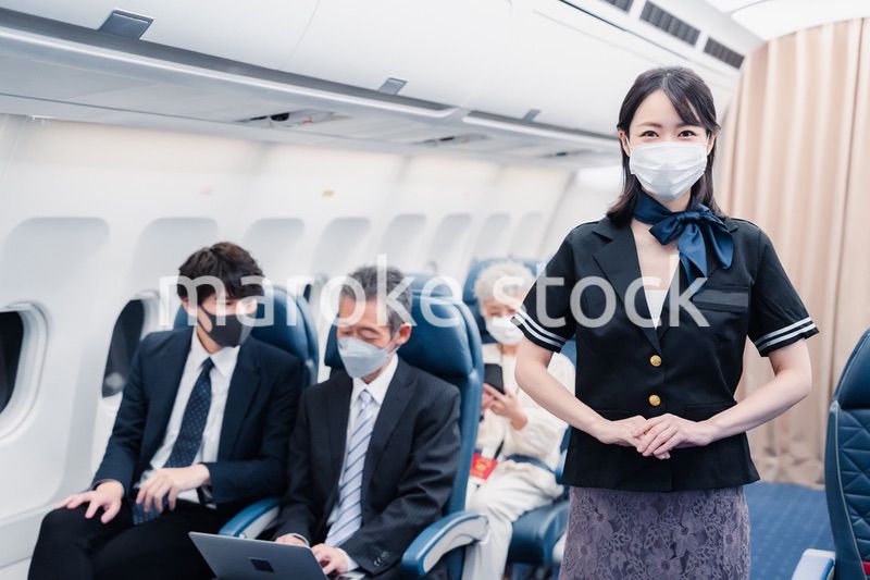 マスクをしてお客様の案内をするキャビンアテンダント