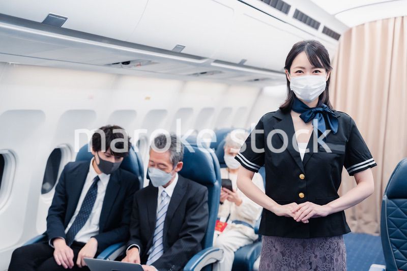マスクをしてお客様の案内をするキャビンアテンダント