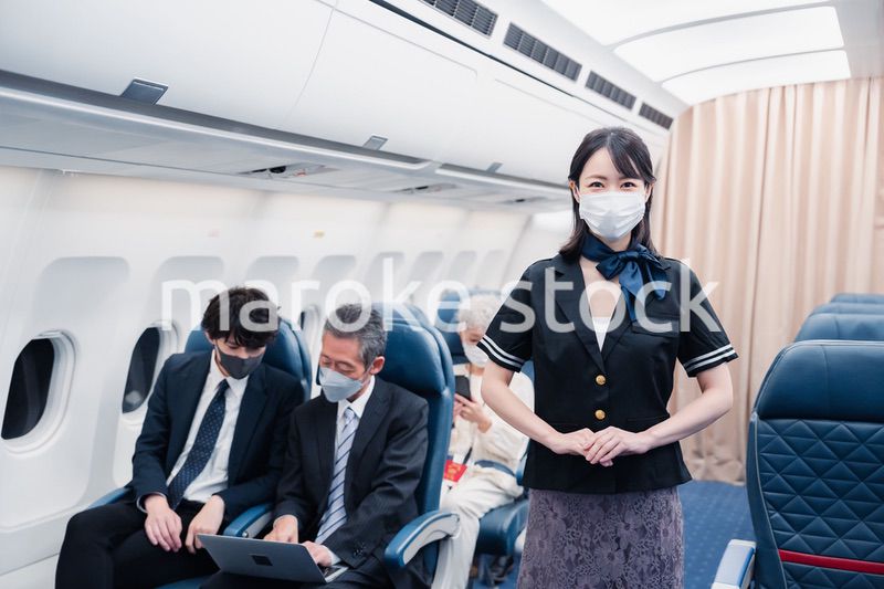 マスクをしてお客様の案内をするキャビンアテンダント