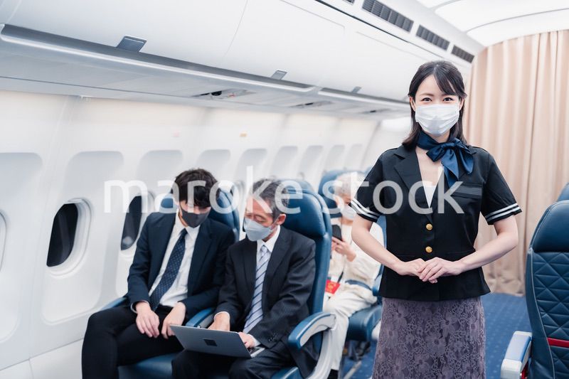 マスクをしてお客様の案内をするキャビンアテンダント
