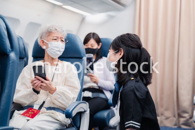 マスクをしてお客様の案内をするキャビンアテンダント