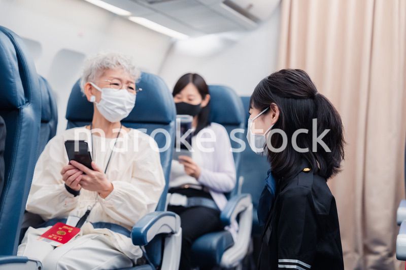 マスクをしてお客様の案内をするキャビンアテンダント