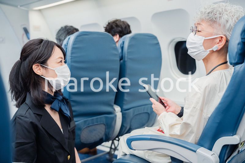 マスクをして機内サービスをする客室乗務員