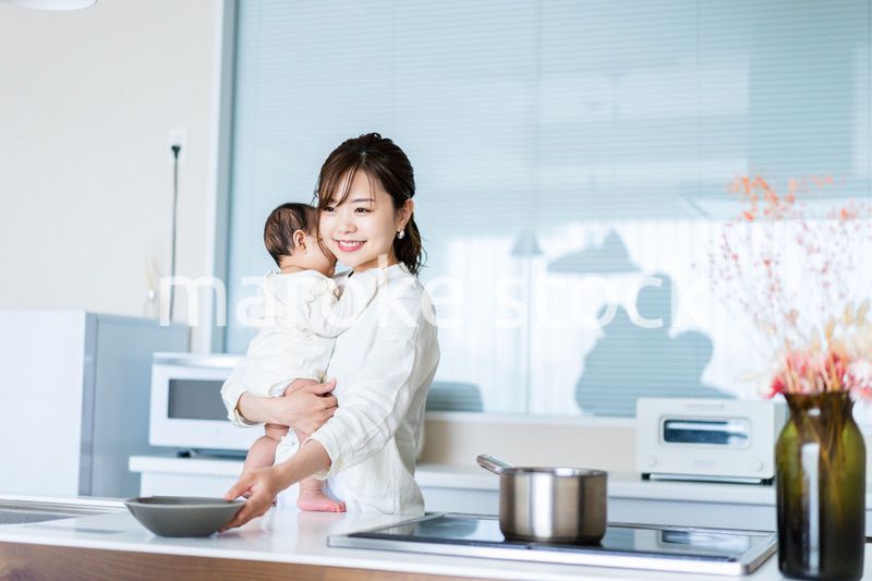 赤ちゃんを抱っこしながら家事をする若い女性