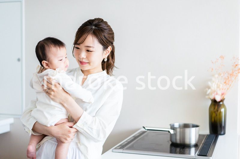 赤ちゃんを抱っこしながら家事をする若い女性