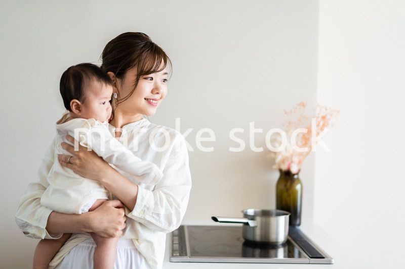 赤ちゃんを抱っこしながら家事をする若い女性