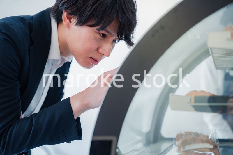 パティスリーでスイーツを買う若い男性