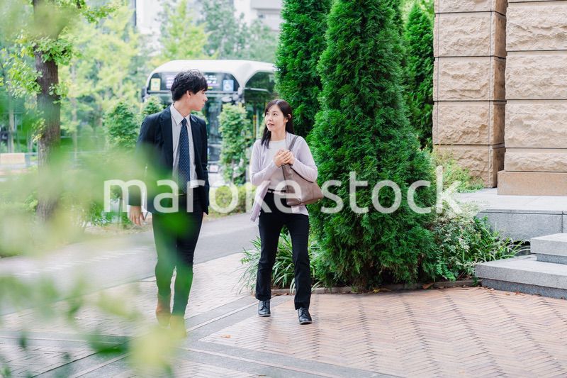 同僚とおしゃべりをしながら歩くビジネスパーソン