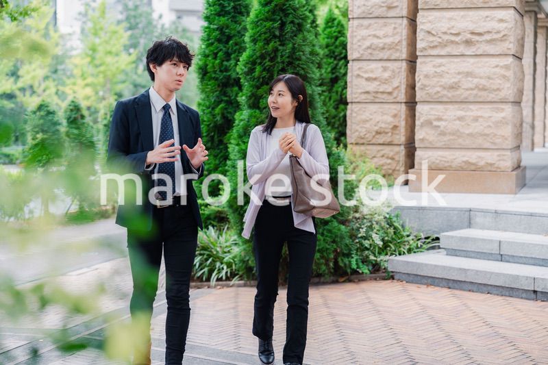 同僚とおしゃべりをしながら歩くビジネスパーソン