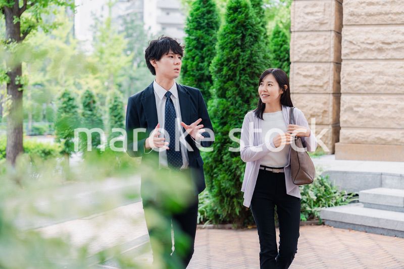 同僚とおしゃべりをしながら歩くビジネスパーソン