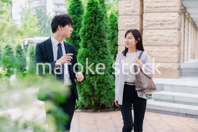 同僚とおしゃべりをしながら歩くビジネスパーソン