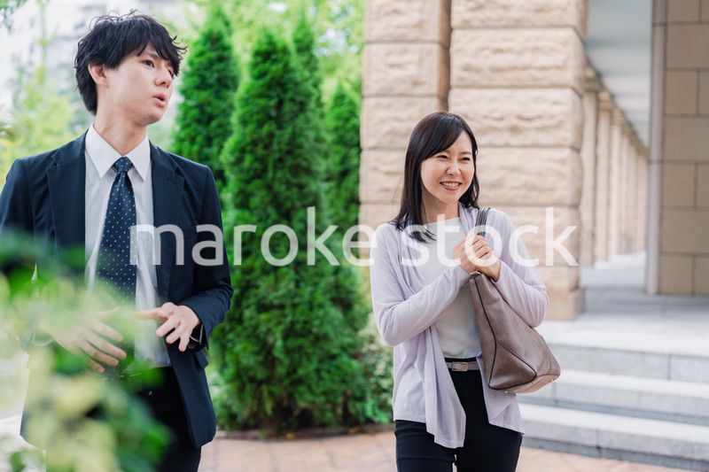 同僚とおしゃべりをしながら歩くビジネスパーソン