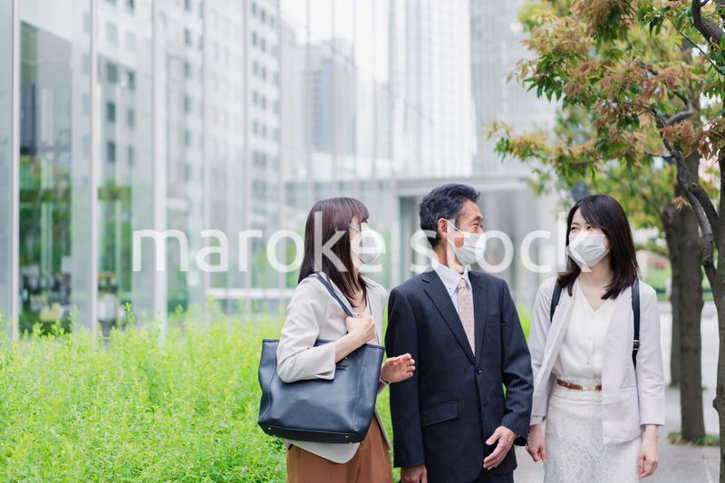 マスクをしてオフィスで立ち話をするビジネスパーソン