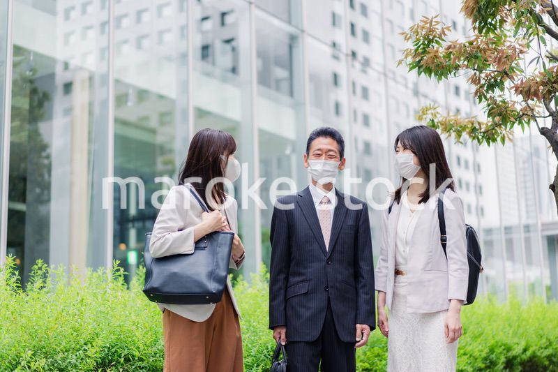 マスクをしてオフィスで立ち話をするビジネスパーソン