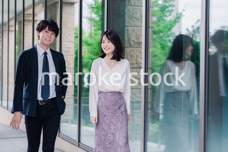 話しながらオフィスを歩く男女のビジネスパーソン