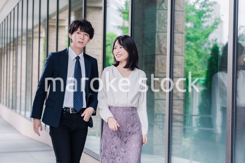 話しながらオフィスを歩く男女のビジネスパーソン