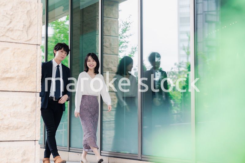 話しながらオフィスを歩く男女のビジネスパーソン