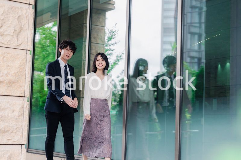 話しながらオフィスを歩く男女のビジネスパーソン