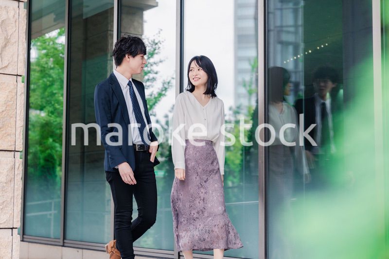 話しながらオフィスを歩く男女のビジネスパーソン