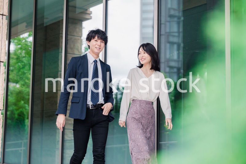 話しながらオフィスを歩く男女のビジネスパーソン