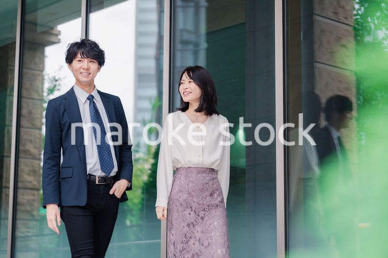 話しながらオフィスを歩く男女のビジネスパーソン