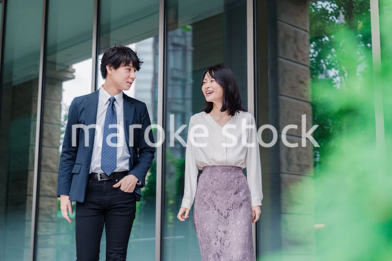 話しながらオフィスを歩く男女のビジネスパーソン