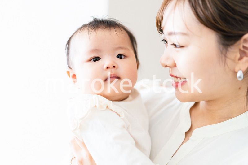 赤ちゃんを抱っこしながら家事をする若い女性