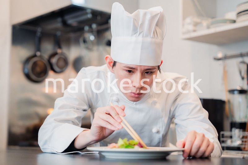 料理の盛り付けをする男性シェフ