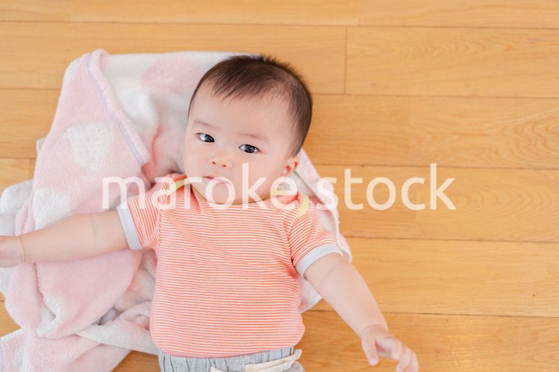 おうちの床に寝転がる赤ちゃん
