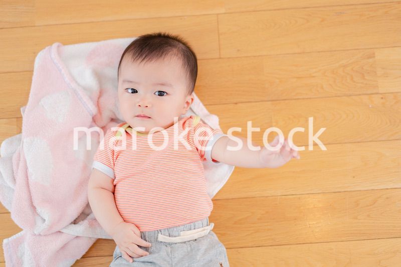 おうちの床に寝転がる赤ちゃん