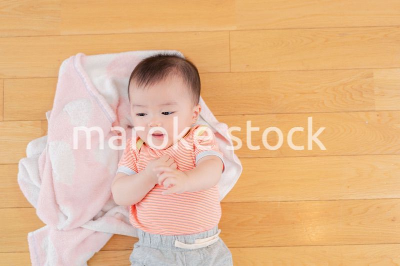 おうちの床に寝転がる赤ちゃん