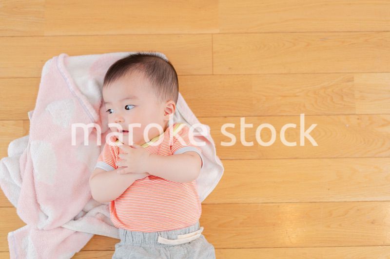 おうちの床に寝転がる赤ちゃん