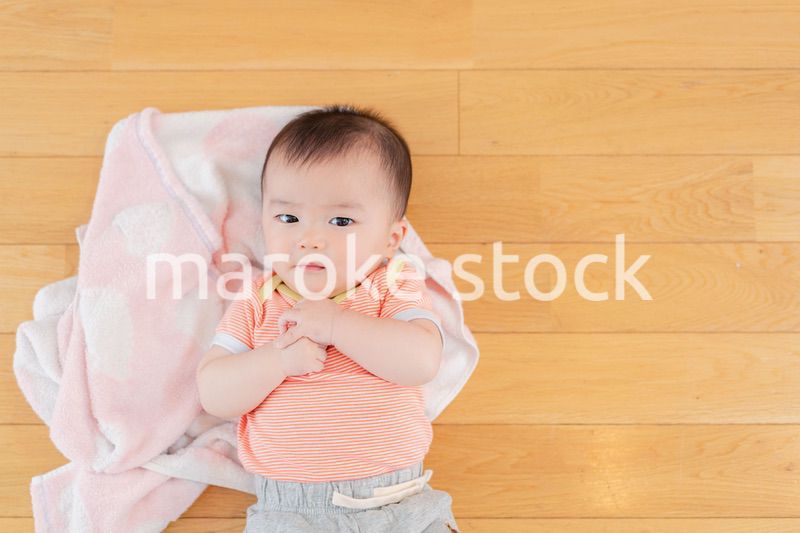 おうちの床に寝転がる赤ちゃん