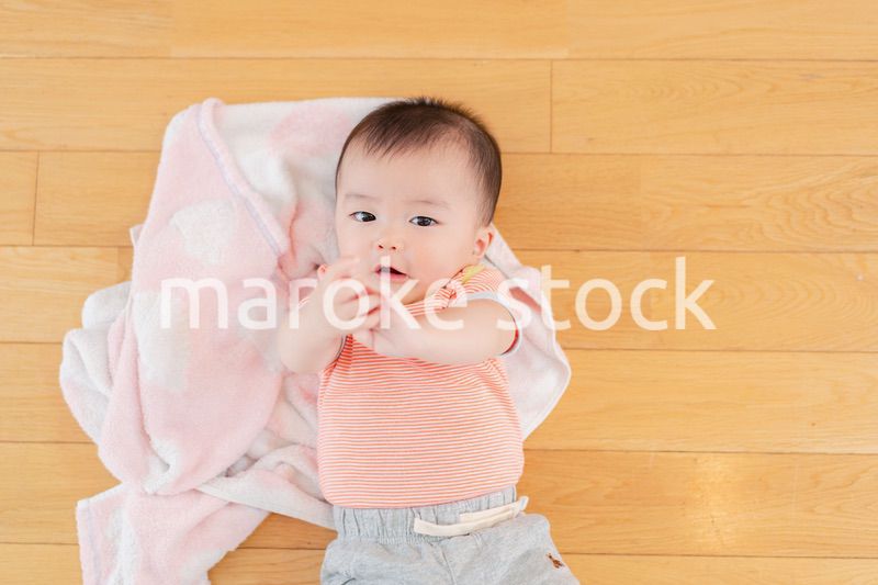 おうちの床に寝転がる赤ちゃん