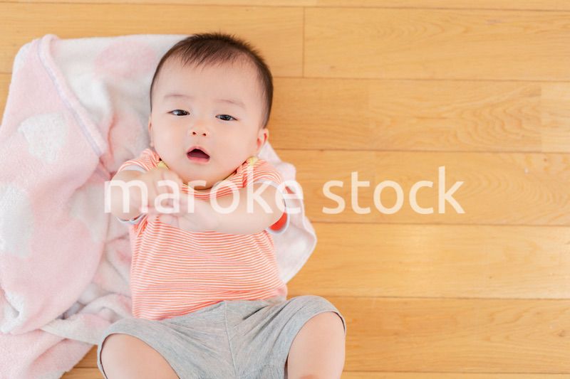 おうちの床に寝転がる赤ちゃん