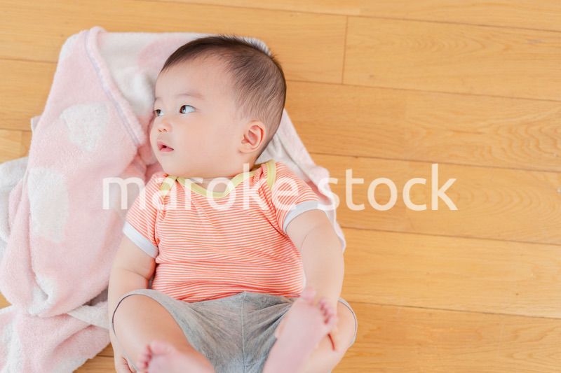 おうちの床に寝転がる赤ちゃん