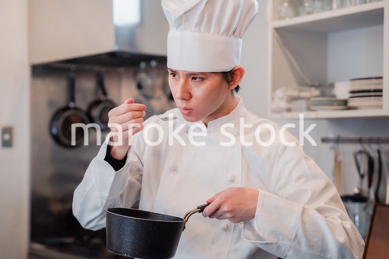 厨房で味見をする男性シェフ