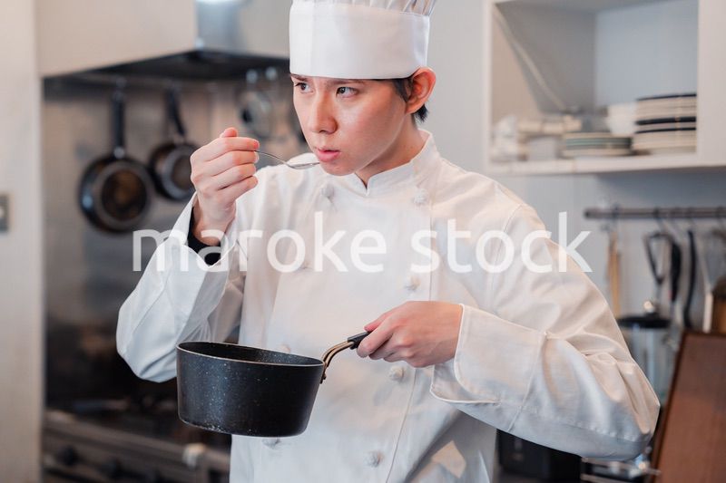 厨房で味見をする男性シェフ