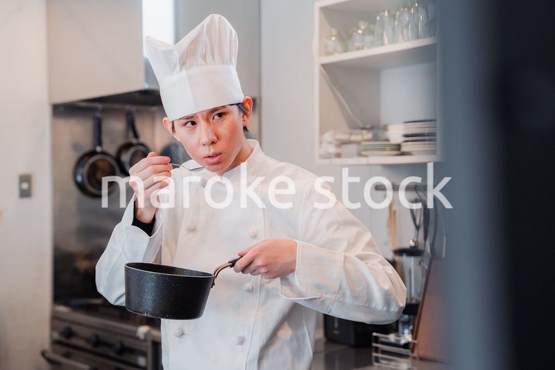 厨房で味見をする男性シェフ