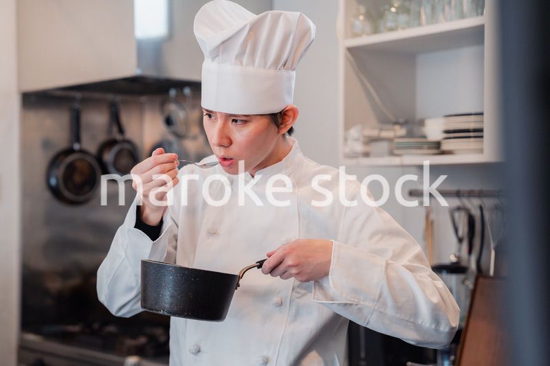 厨房で味見をする男性シェフ