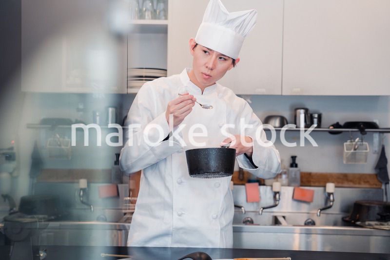厨房で味見をする男性シェフ