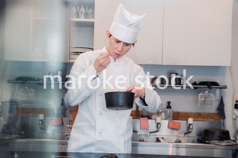 厨房で味見をする男性シェフ