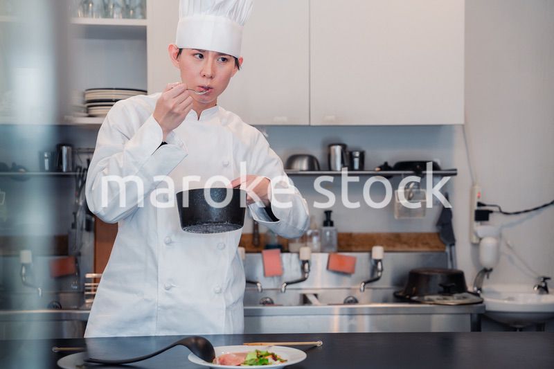 厨房で味見をする男性シェフ