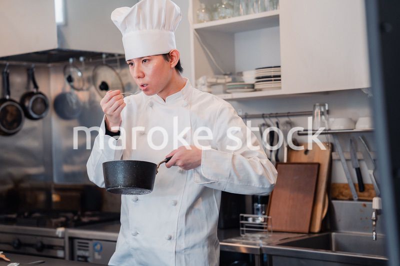 厨房で味見をする男性シェフ