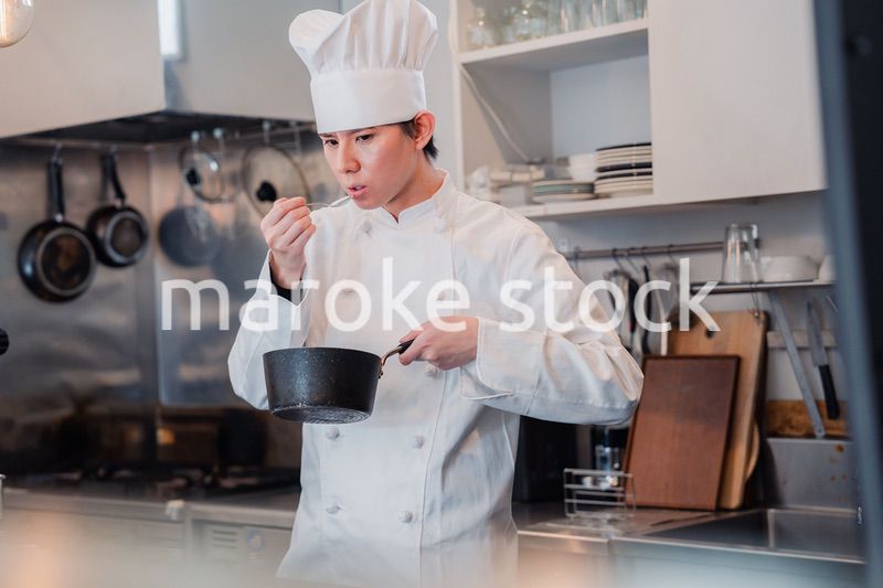 厨房で味見をする男性シェフ