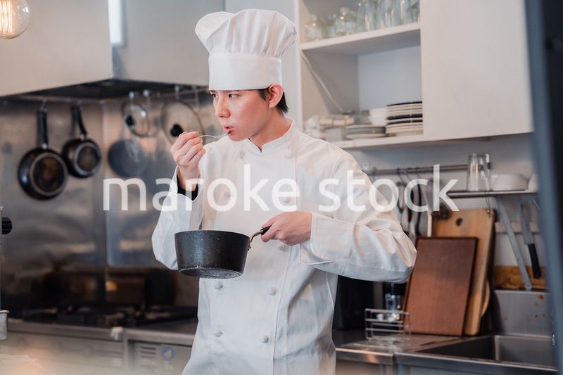 厨房で味見をする男性シェフ