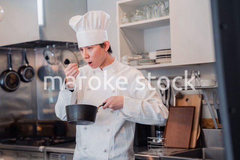 厨房で味見をする男性シェフ