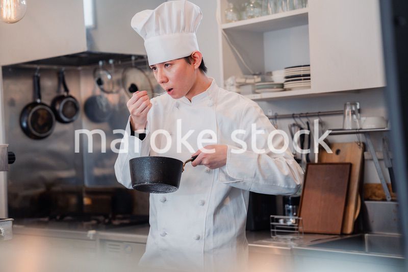 厨房で味見をする男性シェフ
