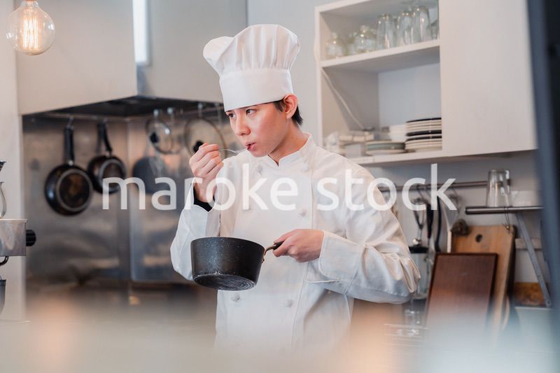 厨房で味見をする男性シェフ